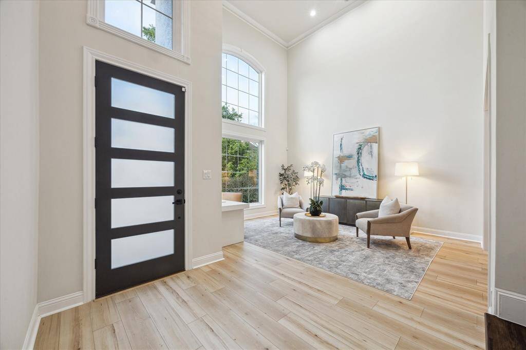 [ENTRANCE] Step into elegance as you enter through the modern front door, a bold statement of style and sophistication. Inside, warm wood floors flow seamlessly, adding an inviting touch to the contemporary design. Soaring high ceilings create an airy, grand ambiance, setting the stage for the refined living spaces beyond.