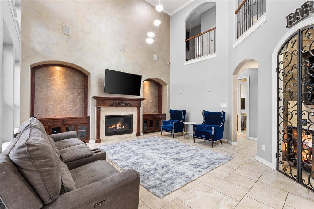 An additional view of the Luxurious Living Room, highlighting the soaring ceilings, balcony overlooking the second floor, and stunning views of the Backyard Oasis, all centered around a custom fireplace for ultimate comfort and relaxation.