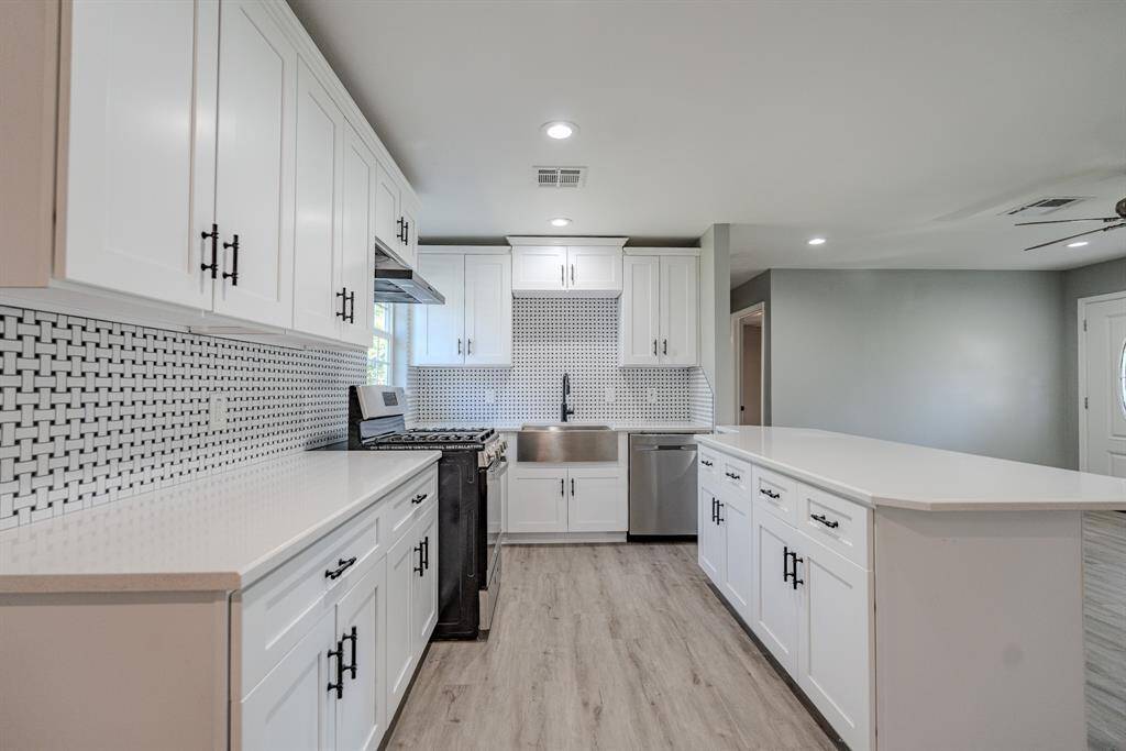 Bright and modern kitchen with sleek and inviting design. The space features expansive countertops and an oversized island that offer ample workspace and seating options.