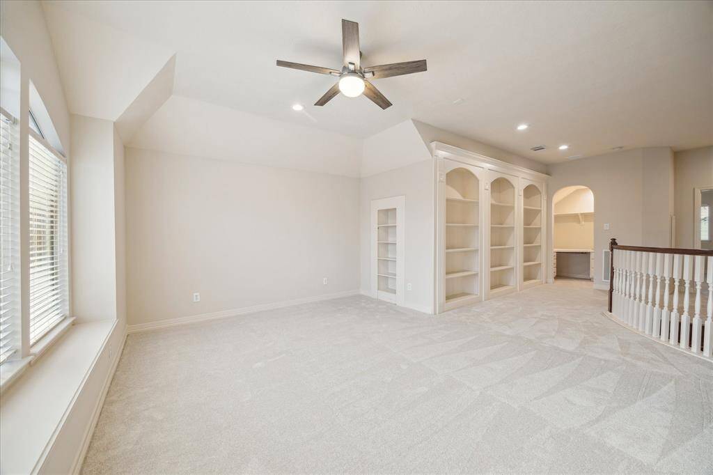 The large game room is a standout feature, offering plenty of space for entertainment. A striking wall of built-ins adds both style and functionality, with shelves for storage and display. Hidden behind this impressive wall lies a secret room.