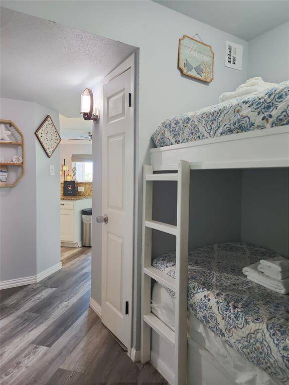 Bright and cozy living room with ocean views, featuring a ceiling fan, comfortable seating, and nautical decor. It includes a mounted TV, fireplace, and sliding glass doors leading to a balcony.