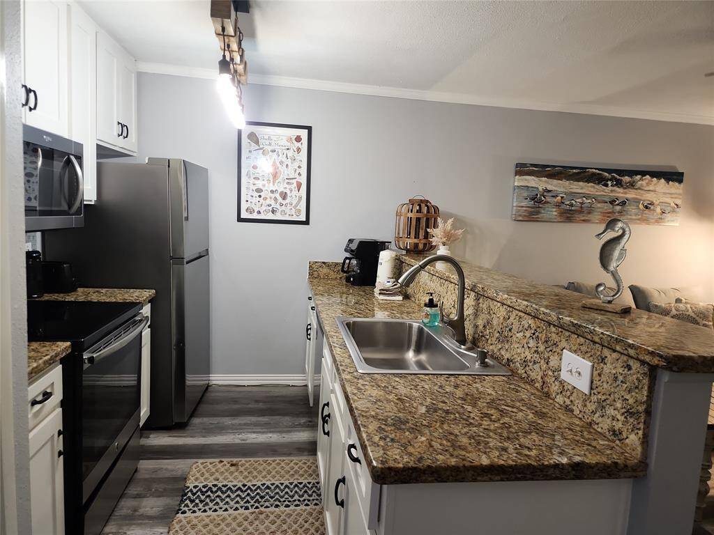 This photo showcases a coastal property with a view of the ocean, lined with palm trees and a clear blue sky. A paved driveway and a nearby path provide easy access to the beach area. Ideal for those seeking a serene, seaside living environment.