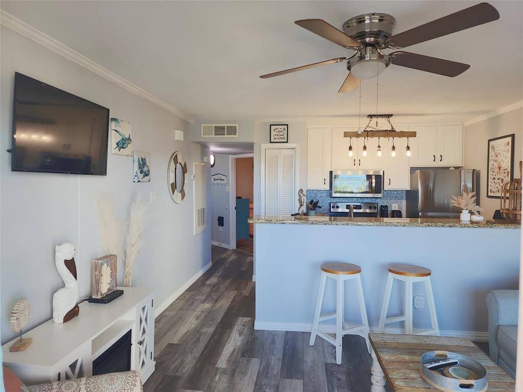This photo showcases a hallway with a coastal-themed decor, featuring a "Welcome to Our Beach House" sign with hooks. The space has light-colored walls and wood flooring, creating a warm and inviting atmosphere.