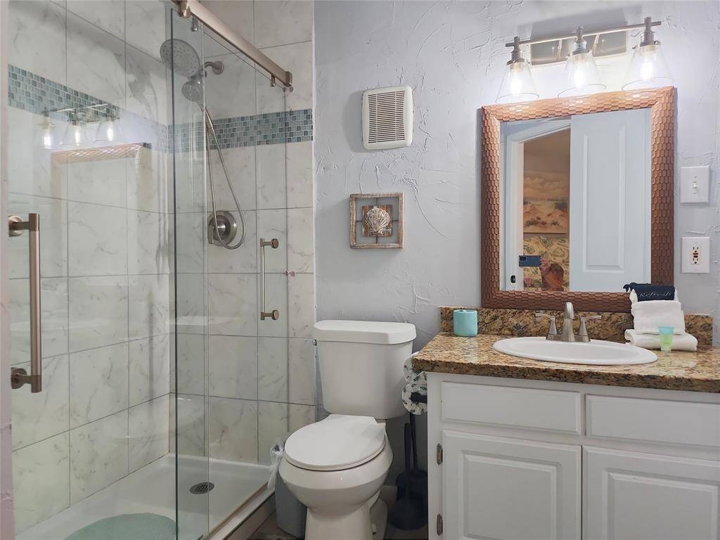 Bright and cozy living space with modern decor. Features a patterned armchair, decorative anchor, wall-mounted TV, and a stylish white console. Accented with sea-themed artwork and turquoise curtains, it offers a fresh and inviting atmosphere.