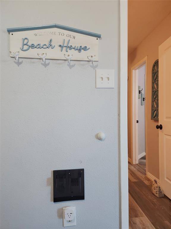 Modern kitchen with granite countertops, stainless steel appliances, and white cabinets. Features a double sink, stylish lighting, and a cozy open layout with artwork and decorative accents.
