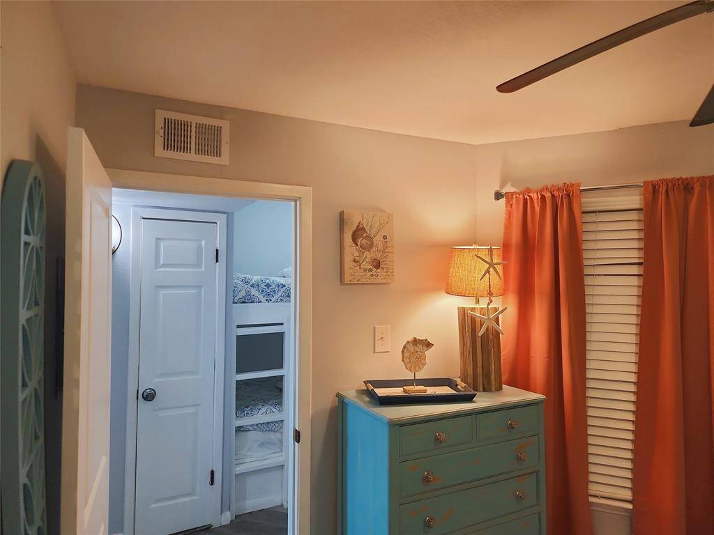 This cozy room features built-in bunk beds with patterned bedding, ideal for kids or guests. The space leads into a bright kitchen area with modern flooring and soft lighting, creating a welcoming atmosphere.