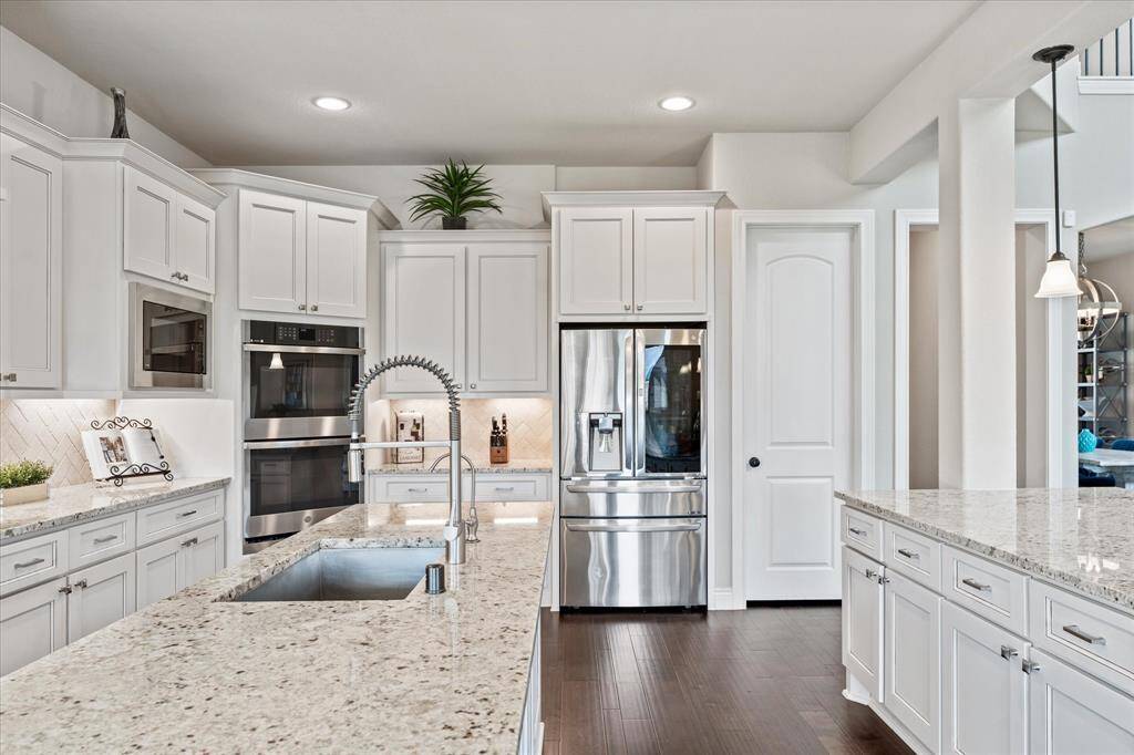 Stainless appliances, double ovens and recessed lighting with pendants over the breakfast bar.