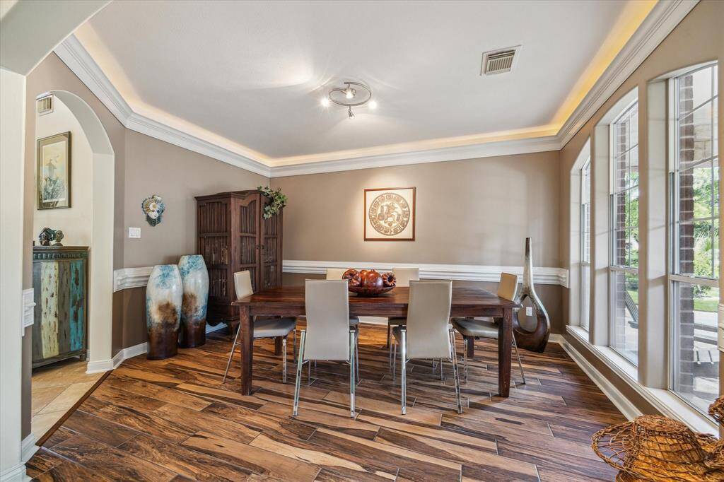 FORMAL DINING ROOM IS READY FOR ENTERTAINING AND ELEGANT DINING - wood flooring, neutral wall colors above and below chair rail, crown molding with cove lighting