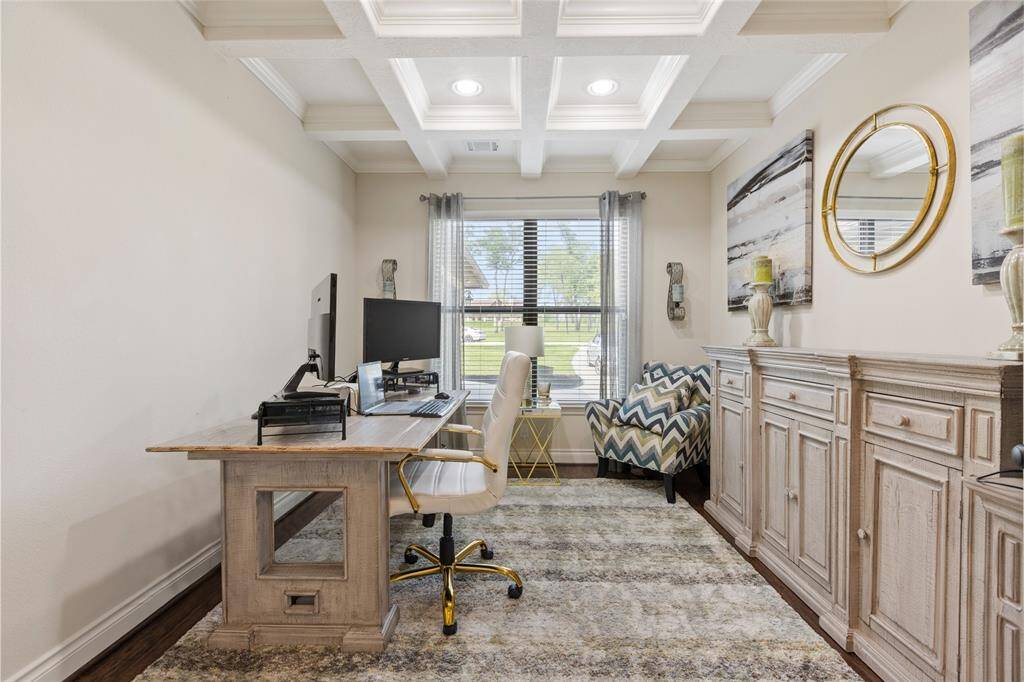 The home office boasts stunning coffered ceilings and is bathed in natural light from its expansive windows, creating an inspiring and elegant workspace.