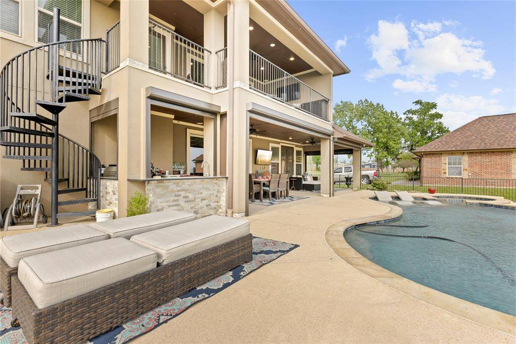 Designed to withstand the elements, the durable iron spiral staircase provides easy outdoor access between the upper balcony and the covered lower patio. Just steps away, the outdoor kitchen is perfect for cooking and entertaining without needing to go inside.