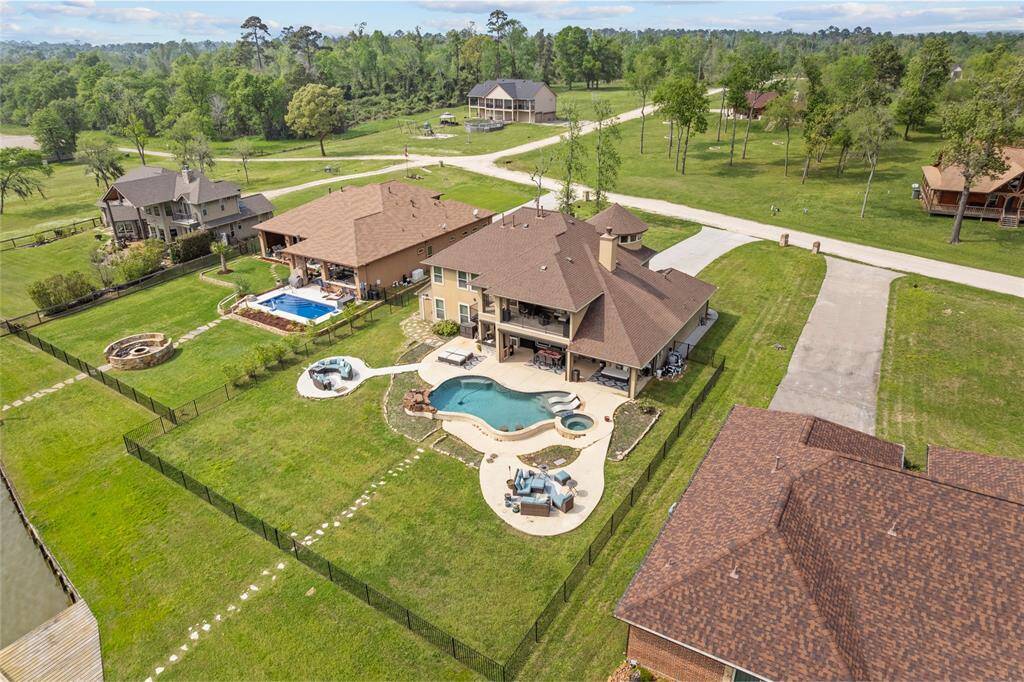 This aerial view captures the back of the home, surrounded by neighboring custom homes and lush wooded areas, offering a private, tranquil setting on a spacious lot.