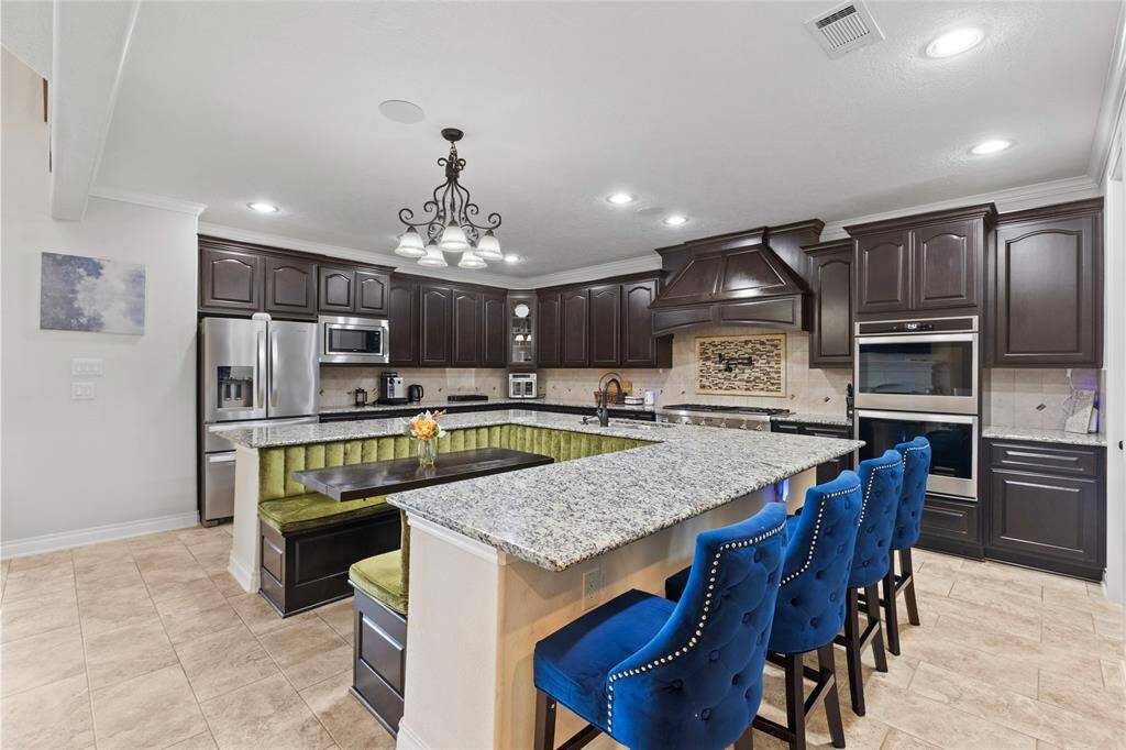 Step into a chef’s dream kitchen featuring granite countertops, custom Kent Moore cabinetry, and a Thermador 48” cooktop with six burners and griddle. Enjoy the convenience of a pot filler, double convection ovens, and undercabinet lighting with sleek outlets.