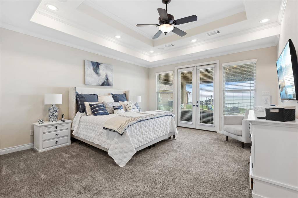 The spacious and inviting primary suite features tray ceiling with recessed lighting that adds depth and warmth. Wake up to stunning lake views and enjoy direct access to the covered patio through private doors. Designed for both comfort and style, this serene space offers a perfect place to relax and unwind.
