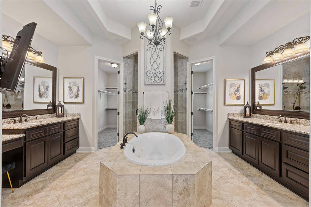 Indulge in the serenity of a spa-like bathroom designed for ultimate relaxation. This luxurious retreat features a double vanity, an oversized shower with dual rain showerheads, and a soaking tub with soothing jets for a true spa experience. The spacious wrap-around walk-in closet offers ample storage and effortless organization, completing this elegant sanctuary.