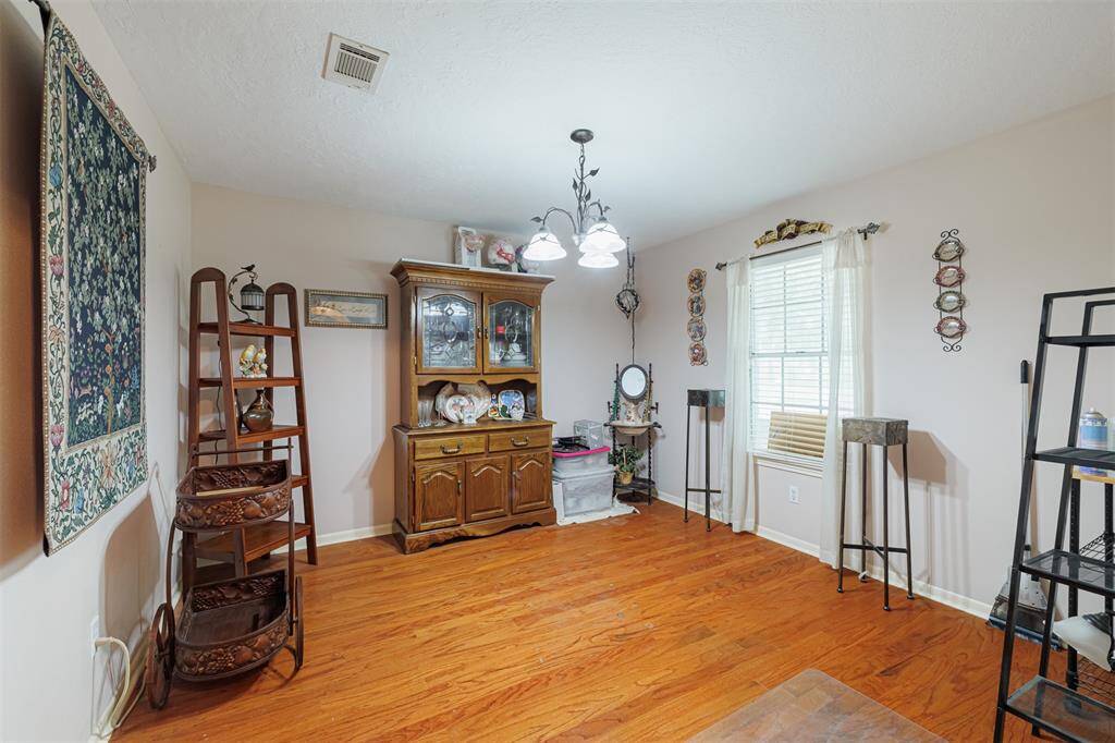 The formal dining room features wood flooring and a chandelier.