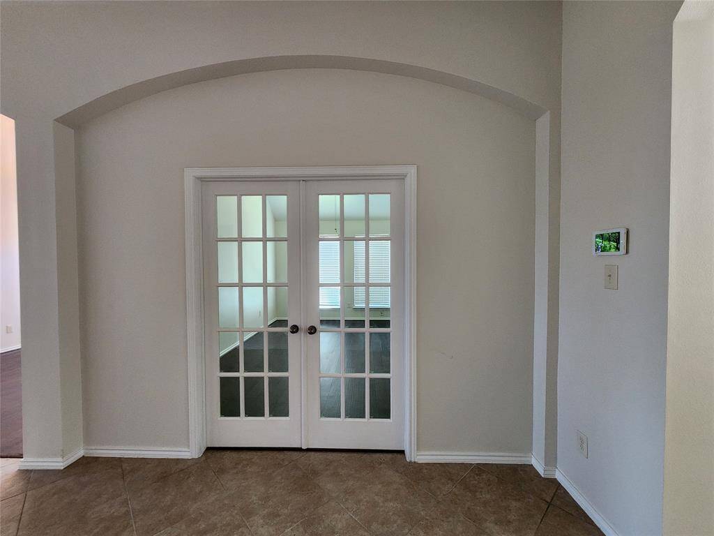 Step through the elegant arched entry into the versatile 5th bedroom or private library, beautifully framed by stately French doors. This inviting space offers the perfect blend of sophistication and functionality, whether used as a peaceful retreat, home office, or guest suite."