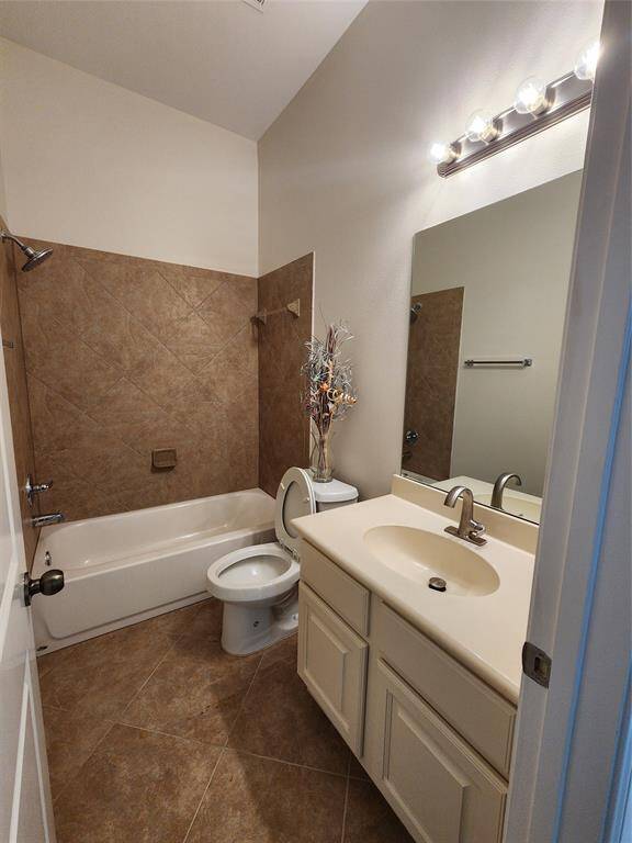 The first bathroom features a stylish and cohesive design with a matching ceramic tile surround for the tub-shower combination and flooring. A sleek vanity cabinet offers ample storage beneath the sink, while a convenient medicine cabinet provides additional space for toiletries and essentials.