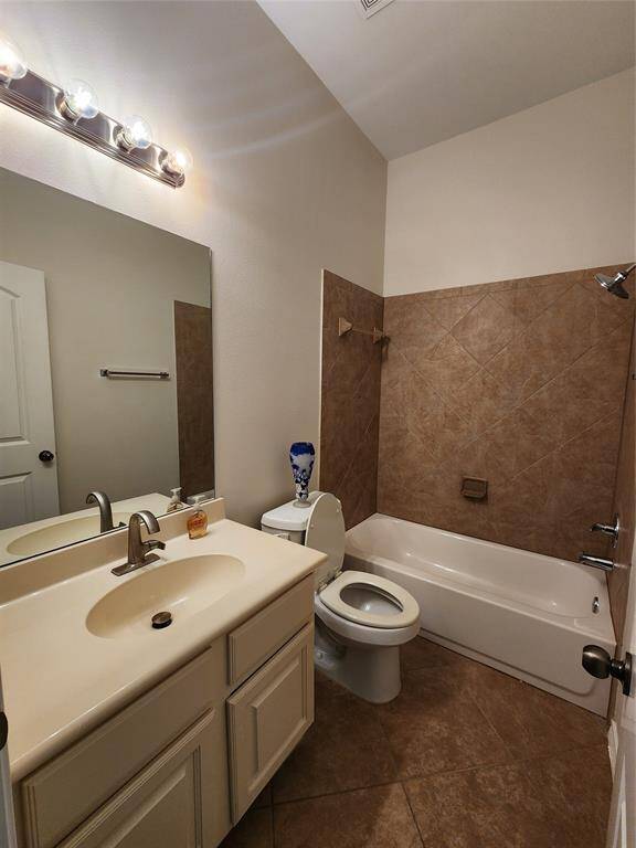 The second bathroom features a stylish and cohesive design with a matching ceramic tile surround for the tub-shower combination and flooring. A sleek vanity cabinet offers ample storage beneath the sink, while a convenient medicine cabinet provides additional space for toiletries and essentials.