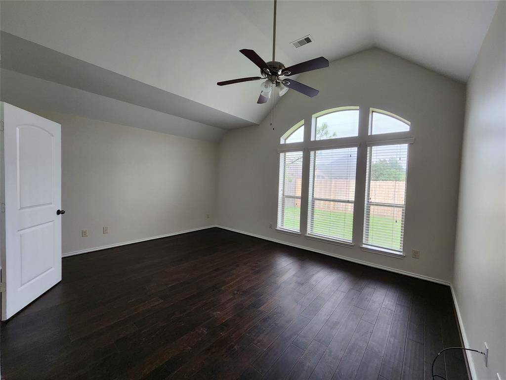 The primary bedroom is a stunning retreat, featuring soaring multi-level high ceilings, a stylish ceiling fan, and gleaming wood floors that add warmth and elegance. Skylight windows invite an abundance of natural light, creating a bright and airy ambiance. Overlooking the serene backyard, this tranquil space offers a peaceful escape with beautiful views.