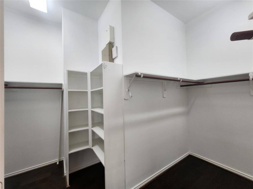 This spacious primary bedroom walk-in closet boasts high ceilings, offering the potential for expanded storage. Thoughtfully designed, it includes two dedicated hanging areas for clothing, along with built-in organizers and shelving, ensuring a well-structured and easily accessible wardrobe space. Perfect for maximizing both functionality and style!