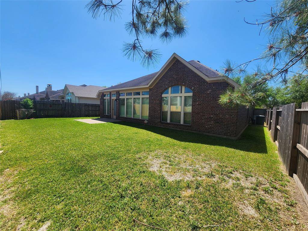 Rear of home and view of the spacious rear yard. Mature landscaping and a front and rear sprinkler system create a lush, well-maintained outdoor oasis.