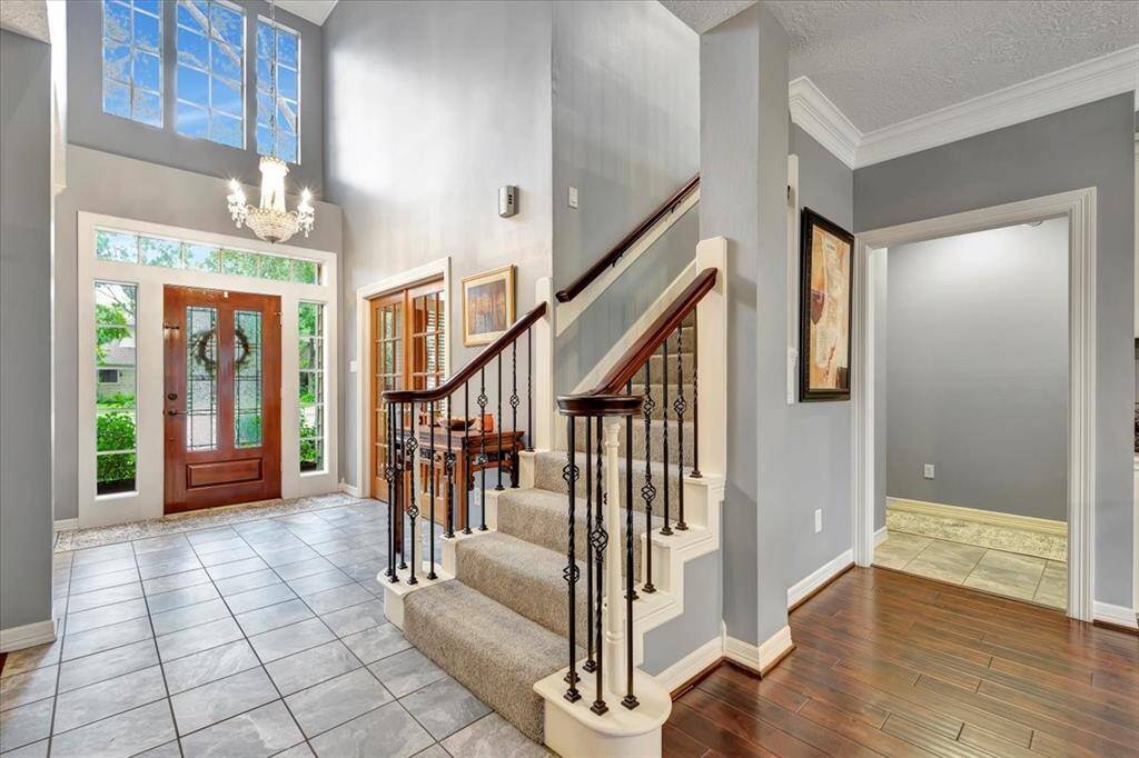 Gracious, light-flooded entry with a crystal chandelier and decorative wrought iron balusters.