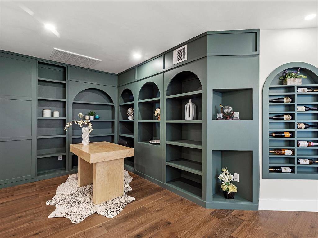 The study or flex space features custom-built shelving with arched niches, wine storage, open display areas, and hidden storage for added functionality and style.