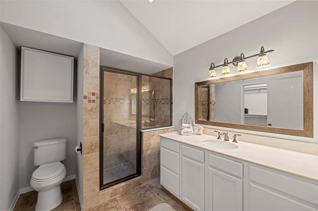 The primary en-suite bathroom features a large vanity with drawers and cabinets for storage, a cabinet above the commode for additional storage, and an oversized glass enclosed shower! The ceiling skylight adds in more of the natural light we love in this home!