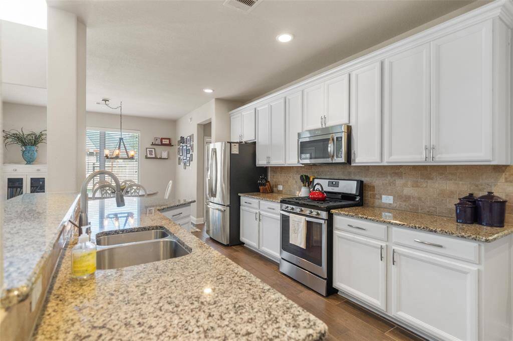 Experience a stunning kitchen with abundant cabinetry, a premium gas range, a convenient built-in microwave, and an elegant travertine backsplash, creating a perfect blend of style and functionality.