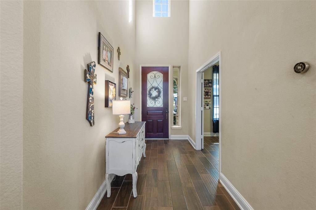 Lovely view upon entry with wood-like tile flooring and wrought iron accented door.