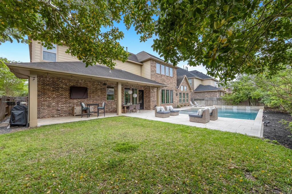 This outdoor entertainment area is a stunning space featuring a travertine , it also includes outdoor seating and a built-in TV, allowing guests to enjoy movies or sports while having fun at the pool!