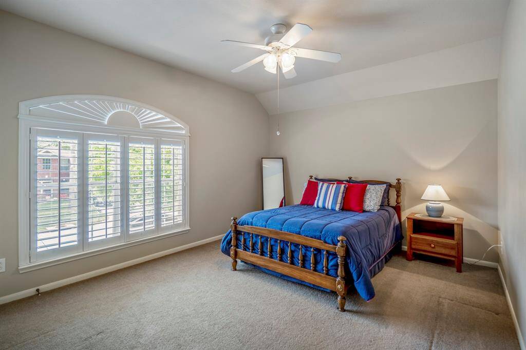 This spacious upstairs bedroom features large plantation shutters on the window overlooking the front of the home, with a vaulted ceiling adding to the room's open and airy feel. All bedrooms in the home offer the added convenience of walk-in closets.