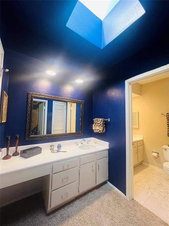 En-suite bath with skylight window, vanity, tub and shower combo