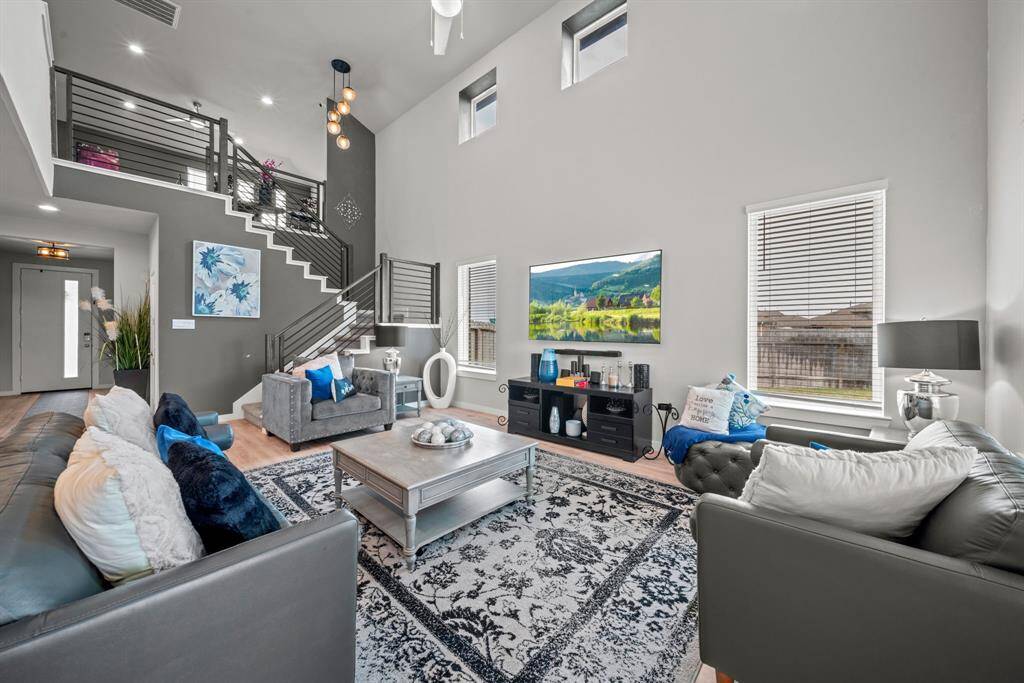 This stunning living room features soaring ceilings, modern lines, and vibrant pops of blue for a chic, inviting vibe.