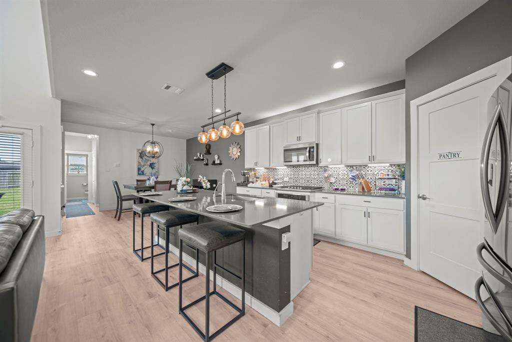 The kitchen shines with modern lighting, crisp white cabinetry, and a spacious island perfect for gatherings.