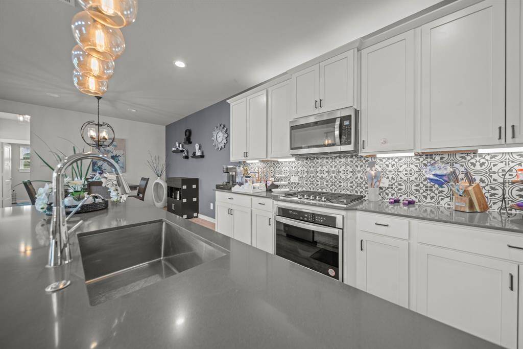Notice the clean lines, quartz countertops and a pop of flair with the backsplash!
