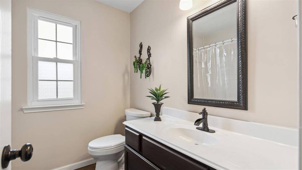 The secondary bathroom offers natural light with its privacy large window and thoughtful layout. Featuring a tub and shower combination, providing functionality for family or guests.