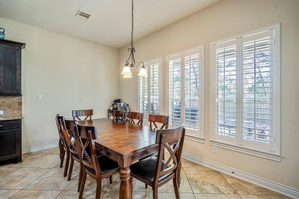 Cozy breakfast nook with hanging lights and wall of windows featuring plantation shutters.