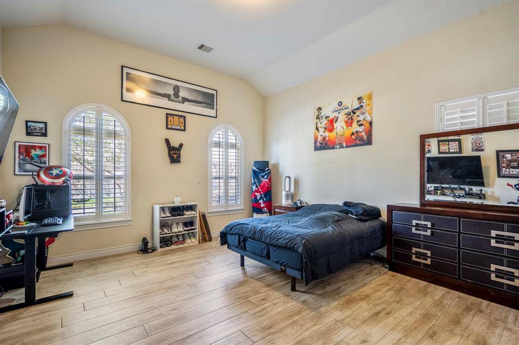 Spacious downstairs en-suite bedroom with light wood-look tile flooring, arched plantation windows.