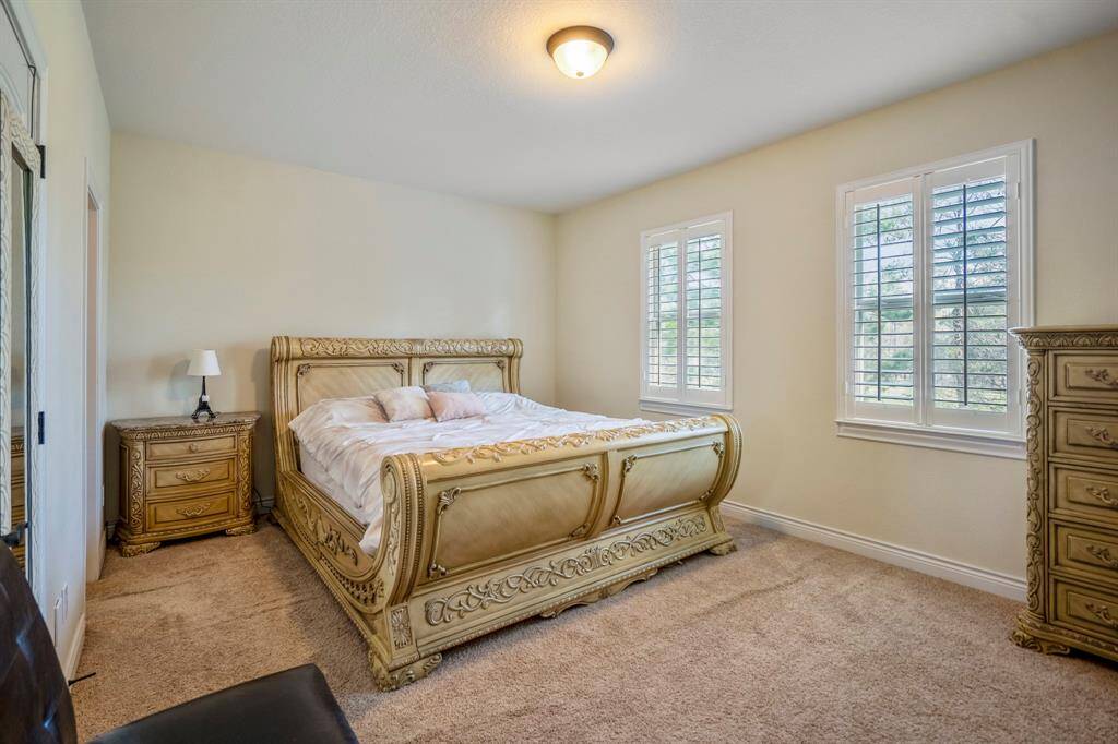 Spacious upstairs bedroom featuring plush carpet, large windows with plantation shutters.