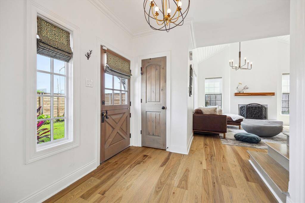 This photo showcases a bright entryway with hardwood floors and dutch front door. The entry leads into the cozy living room