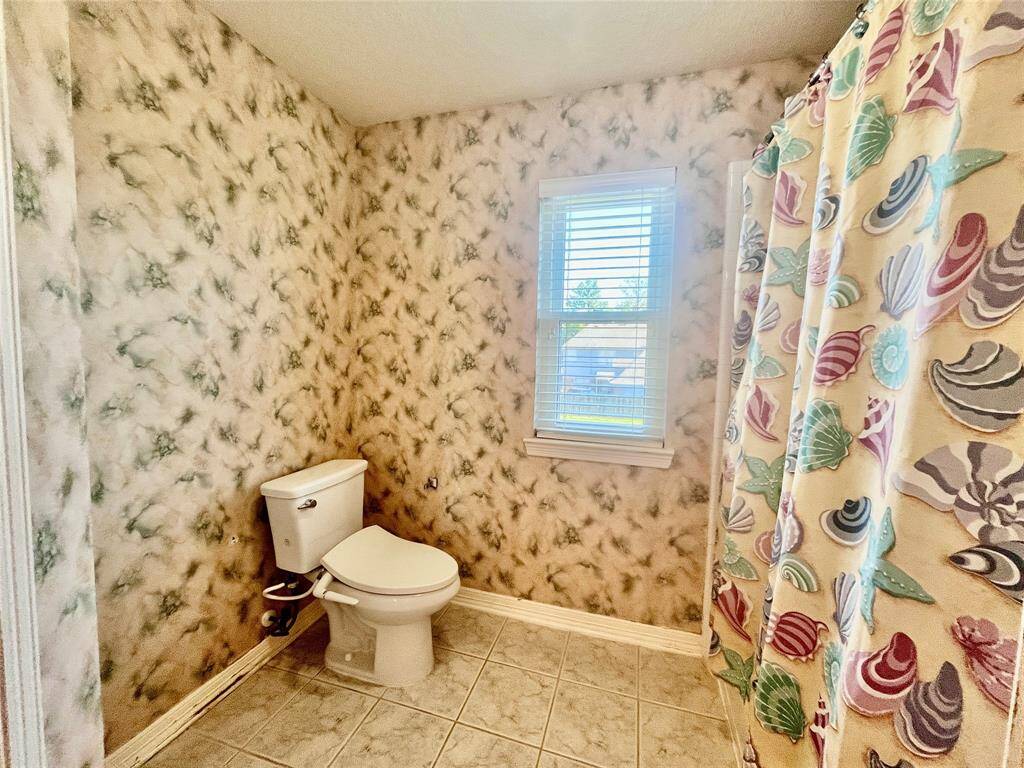 Cozy bathroom with natural light, featuring a charming shower area and serene tile flooring.