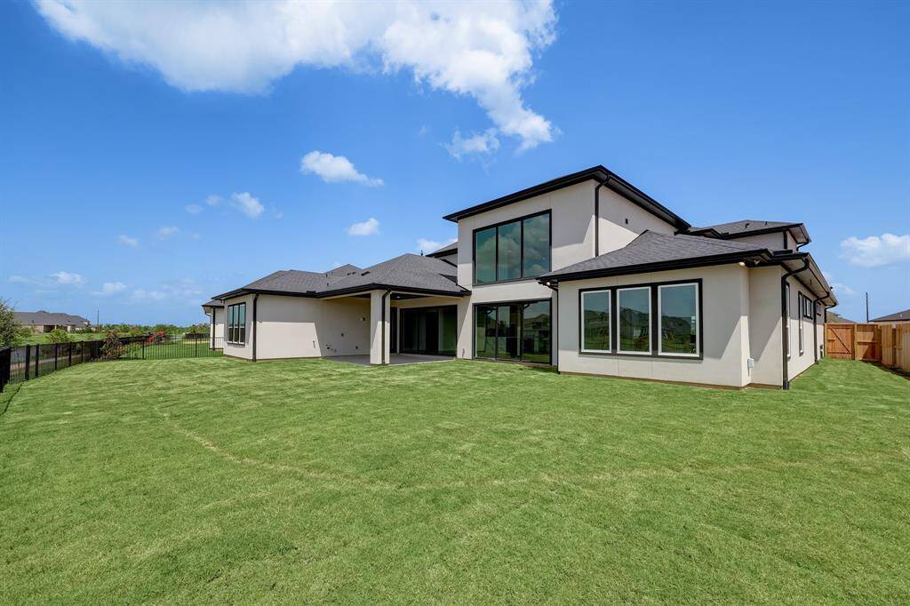 Spacious modern home with a large backyard, featuring clean lines and ample windows for natural light. Ideal for outdoor activities and entertaining.