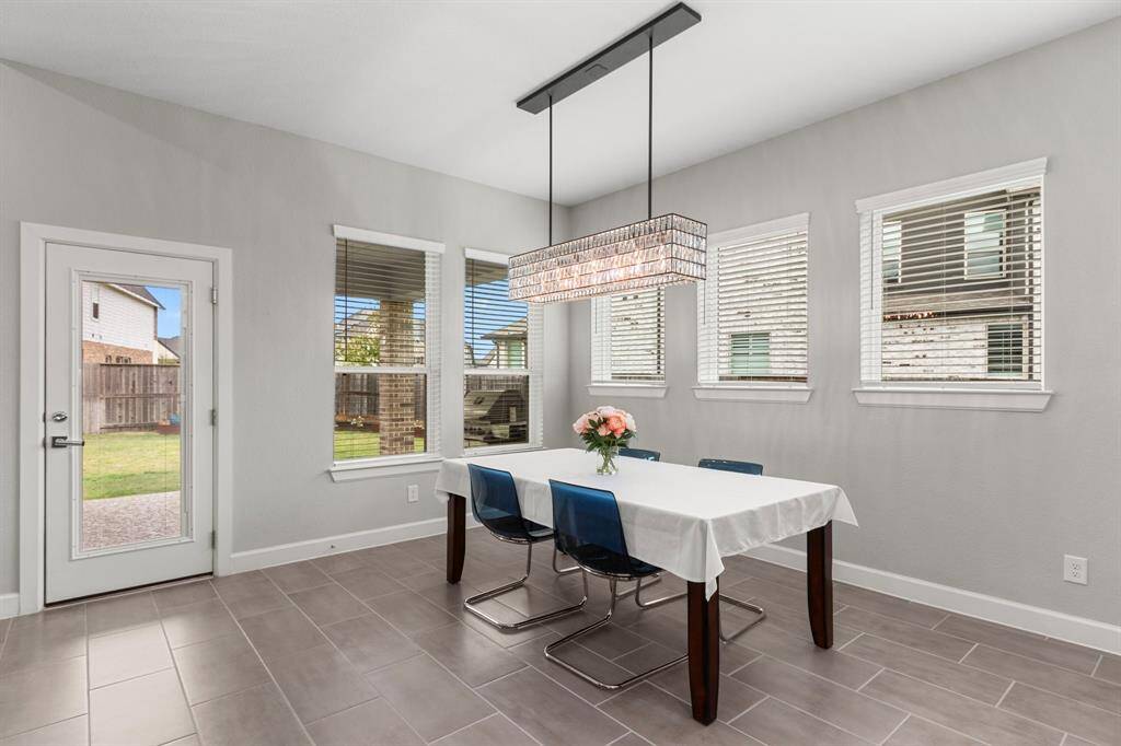 The dining area is ideally located for indoor-outdoor entertaining. This room is open to the living room, kitchen, and back patio, and has more than enough space for your large dining table! The Pottery Barn Adeline Crystal rectangular chandelier adds  designer touch without distracting from the views to the back patio and beyond. The neutral tile flooring is ideal for easy clean-up, or you have more than enough space for a large rug to define this space and add your personal touch to it.