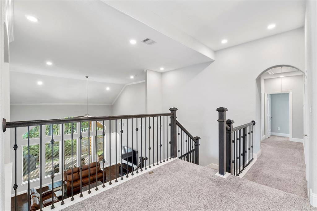 This well-lit upper landing area has a wow factor up against these elegant iron railings. Open view to a living area below, large windows, and an archway leading to additional rooms. Again, the neutral color palette makes this easy to accommodate multiple styles.