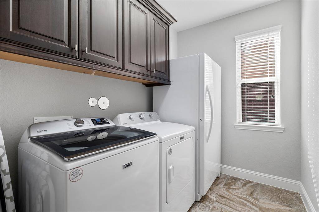 Laundry room  has space for a washer, dryer, and a refrigerator. Cabinets for extra storage space.