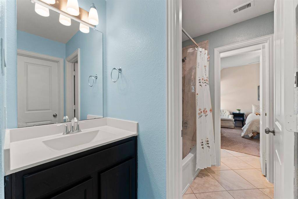 A shared shower area features separate vanities