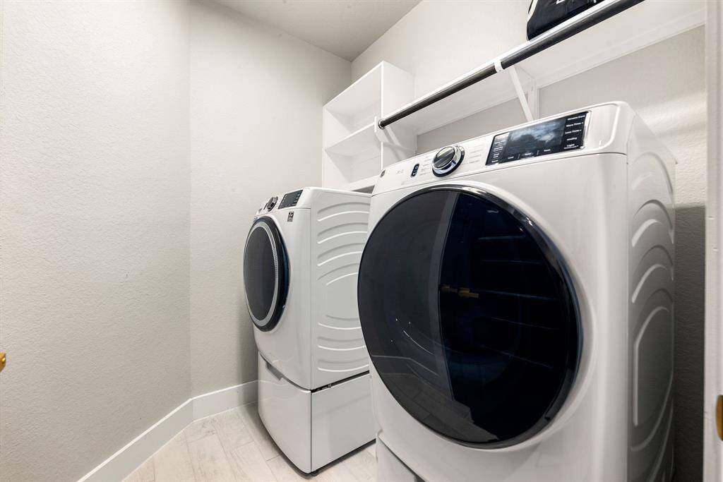 Enjoy the convenience of this spacious laundry area, complete with built-in shelving and ample workspace, designed to simplify your daily routine.