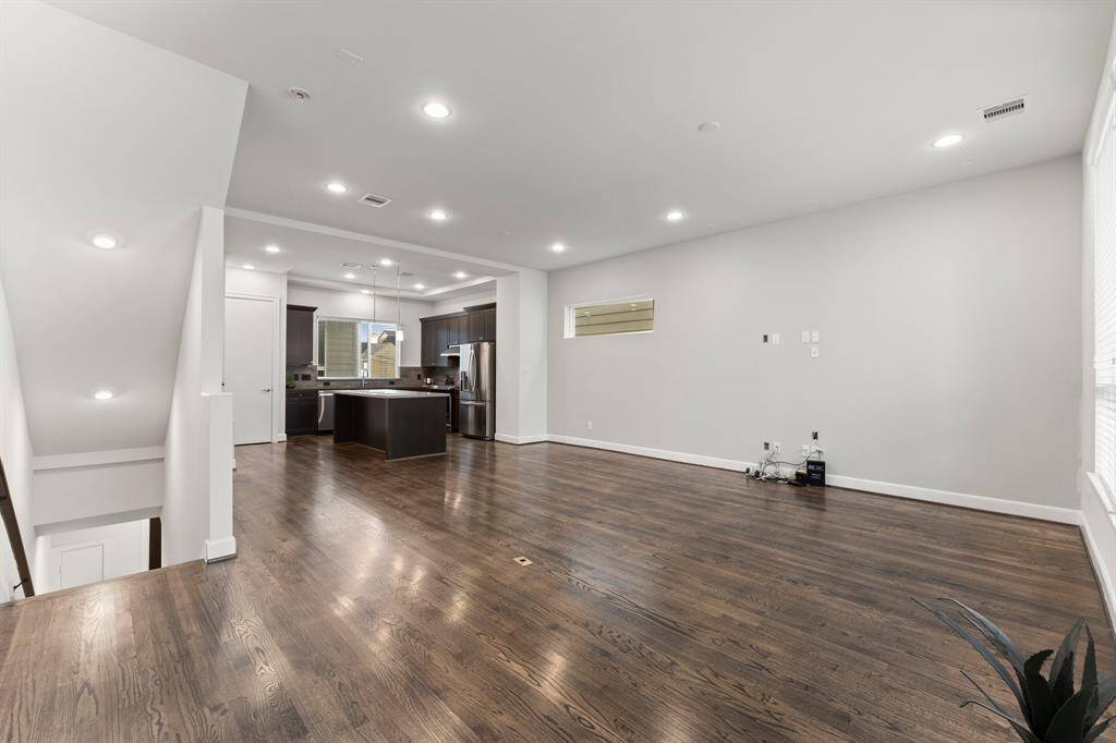 The second floor showcases a spacious, open-concept living area with hardwood floors and modern recessed lighting.