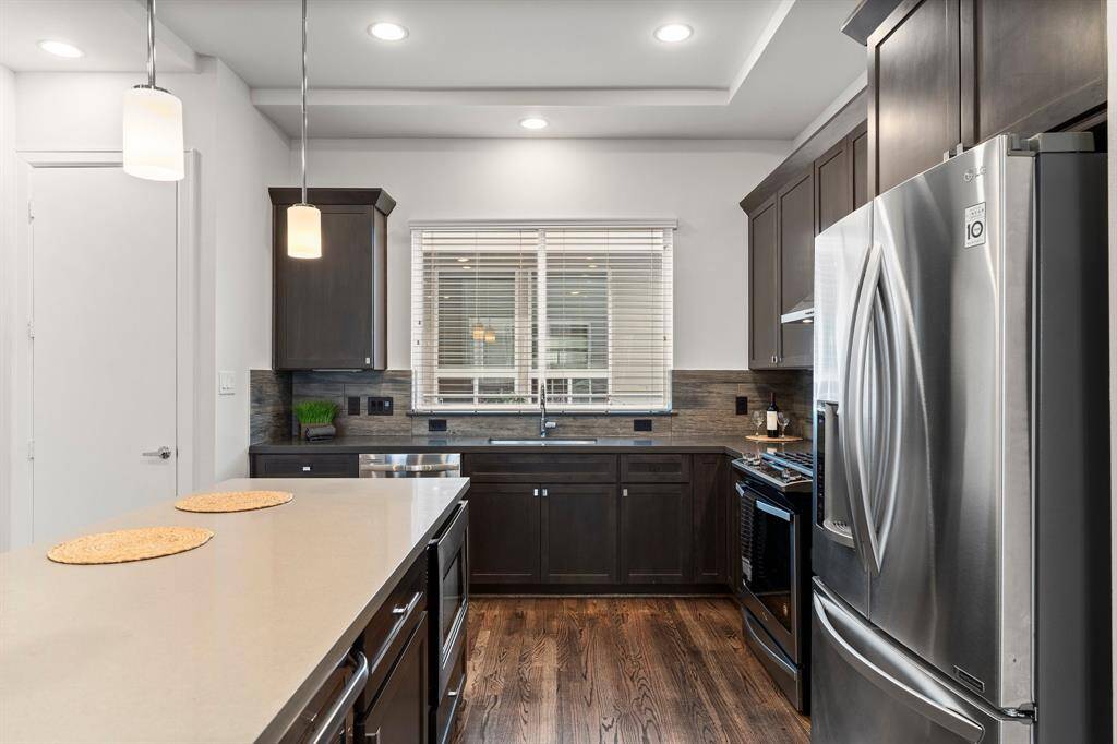 There is ample counter space and a backsplash that complements the dark wood flooring.